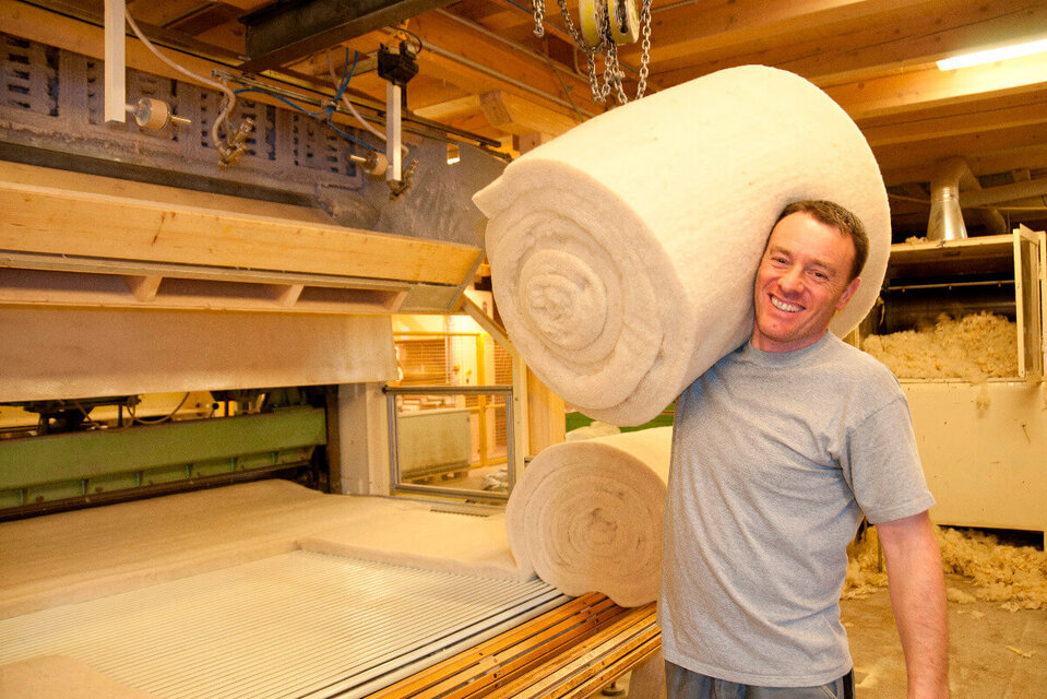 Villgrater Natur Ein männlichter Mitarbeiter trägt einen Ballen Schafwolle auf seiner Schulter