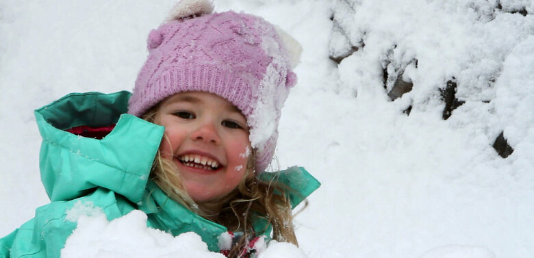 Spielplatz Schnee Ein Kind spielt fröhlich im frischen Schnee