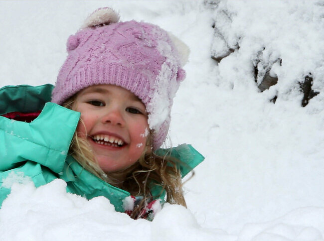 Spielplatz Schnee Ein Kind spielt fröhlich im frischen Schnee