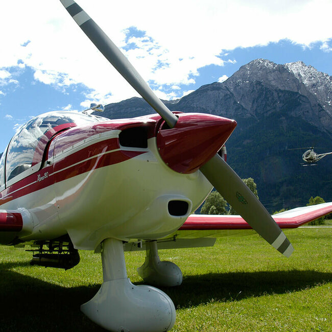 Motorflieger Nahaufnahme eines rot-weißen Motorfliegers auf dem Nikolsdorfer Flugplatz. Im Hintergrund startet gerade ein Hubschrauber.