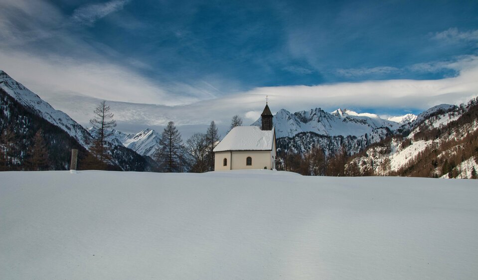 Die verschneite Bichl Kapelle umringt von tiefen Schneefeldern.