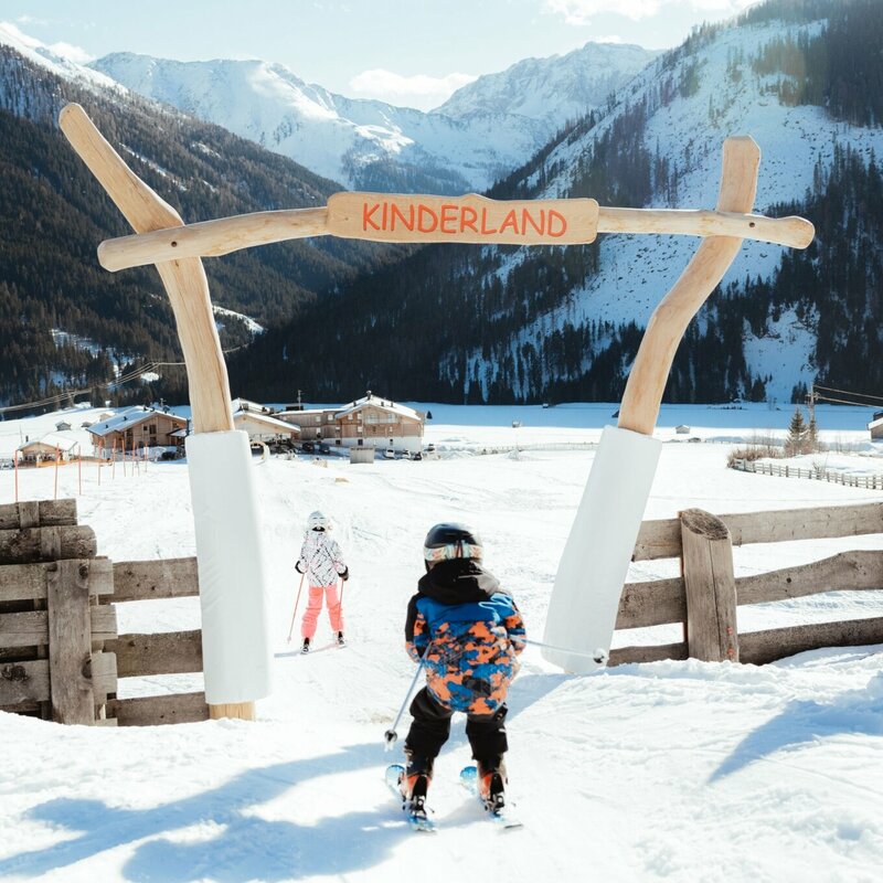 Kinderland Obertilliach Skifahren '22 Ein Kind passiert auf Ski den Eingang ins Kinderland im Familienskigebiet Golzentipp in Obertilliach.
