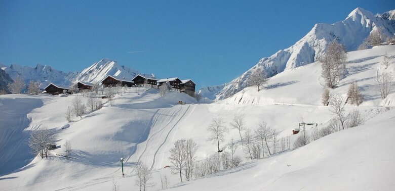 Skifahren beim Bichllift Das schneebedeckte Skigebiet Bichllift. Blick auf einen Skilift und mehrere Gebäude auf einem Hügel.