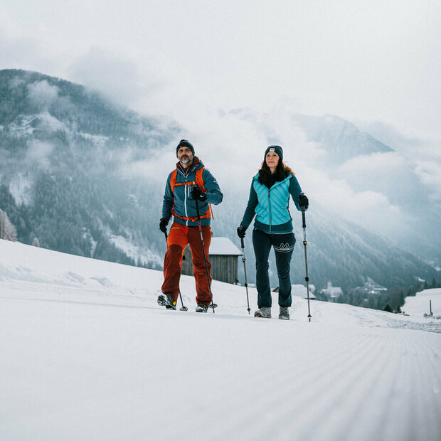 Ein Pärchen wandert auf perfekt präparierten Winterwanderwegen durch Osttirols Winterlandschaft.