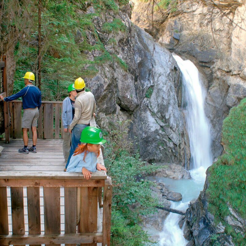 Aussichtskanzel Vier Personen stehen fasziniert auf der Aussichtskanzel des Wasserschaupfades und beobachten das tosend herabschießende Wasser in der Schlucht.