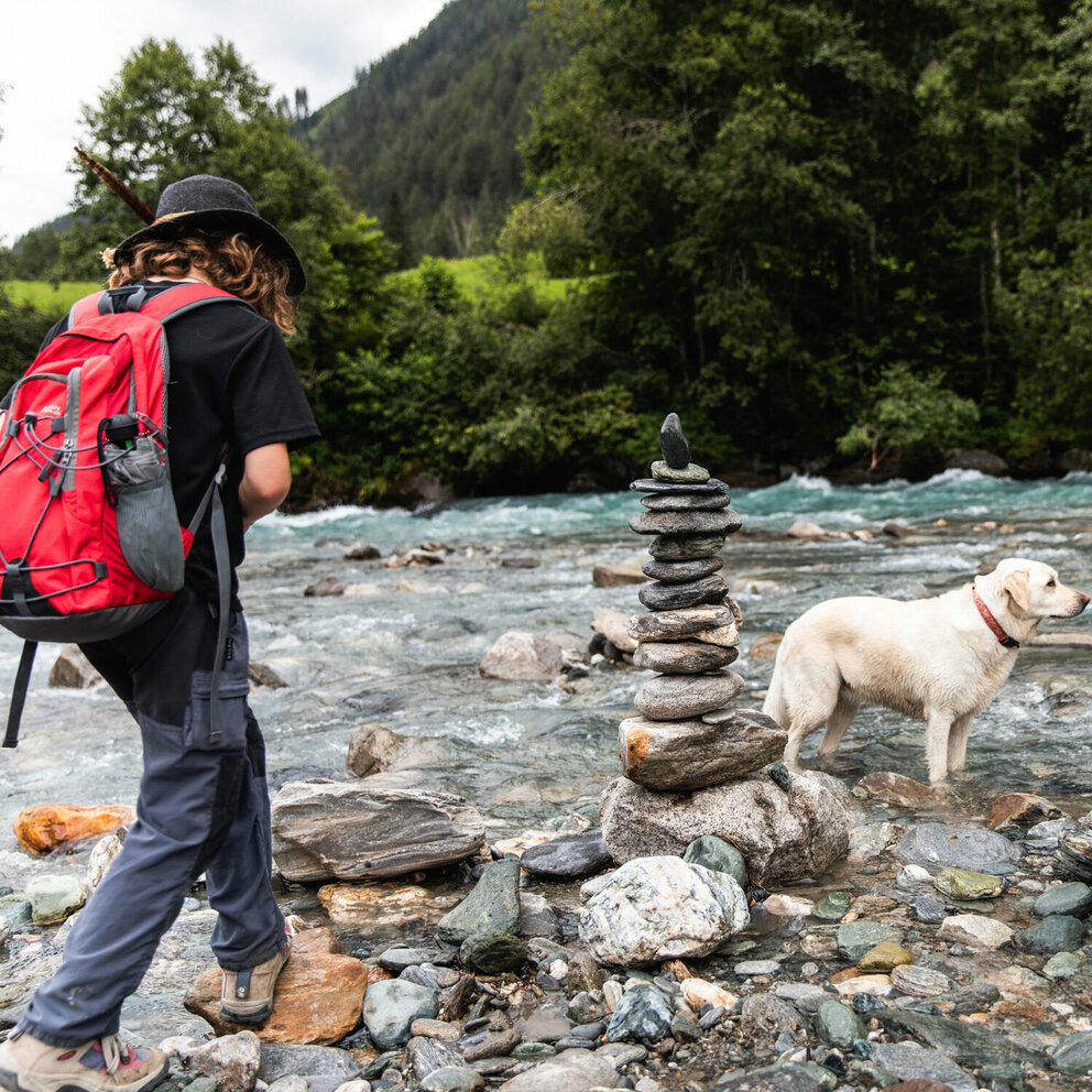 Iseltrail-Hund2020-KindmitHund2 Ein Kind mit einem roten Rucksack wandert mit einem Hund am Iseltrail.