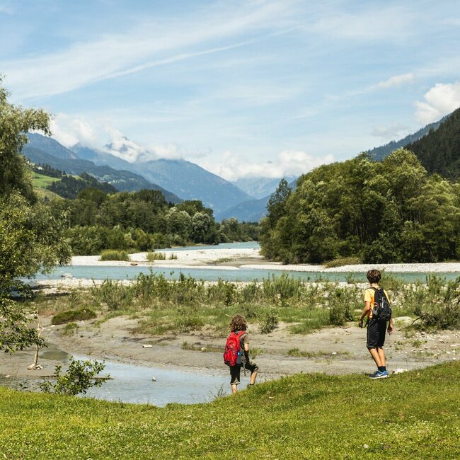 Iseltrail Etappe 1 Zwei Kinder stehen am Ufer der Isel und blicken auf die Sandbänke im Fluss.