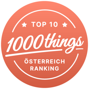 Ein lachsfarbener Kreis mit dem Schriftzug Top 10 1000 things Österreich Ranking.