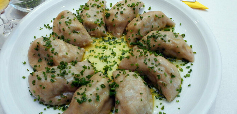 Osstiroler Schlipfkrapfen Osttiroler Schlipfkrapfen mit Schnittlauch und geschmolzener Butter auf einem weißen Teller angerichtet.