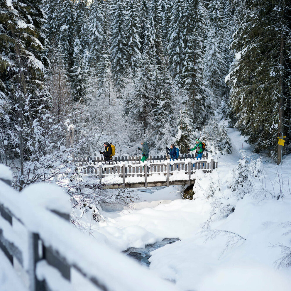Ranger Winterzauber Defereggental Schneeschuhwanderer:innen überqueren eine Brücke bei der Wanderung im Defereggental