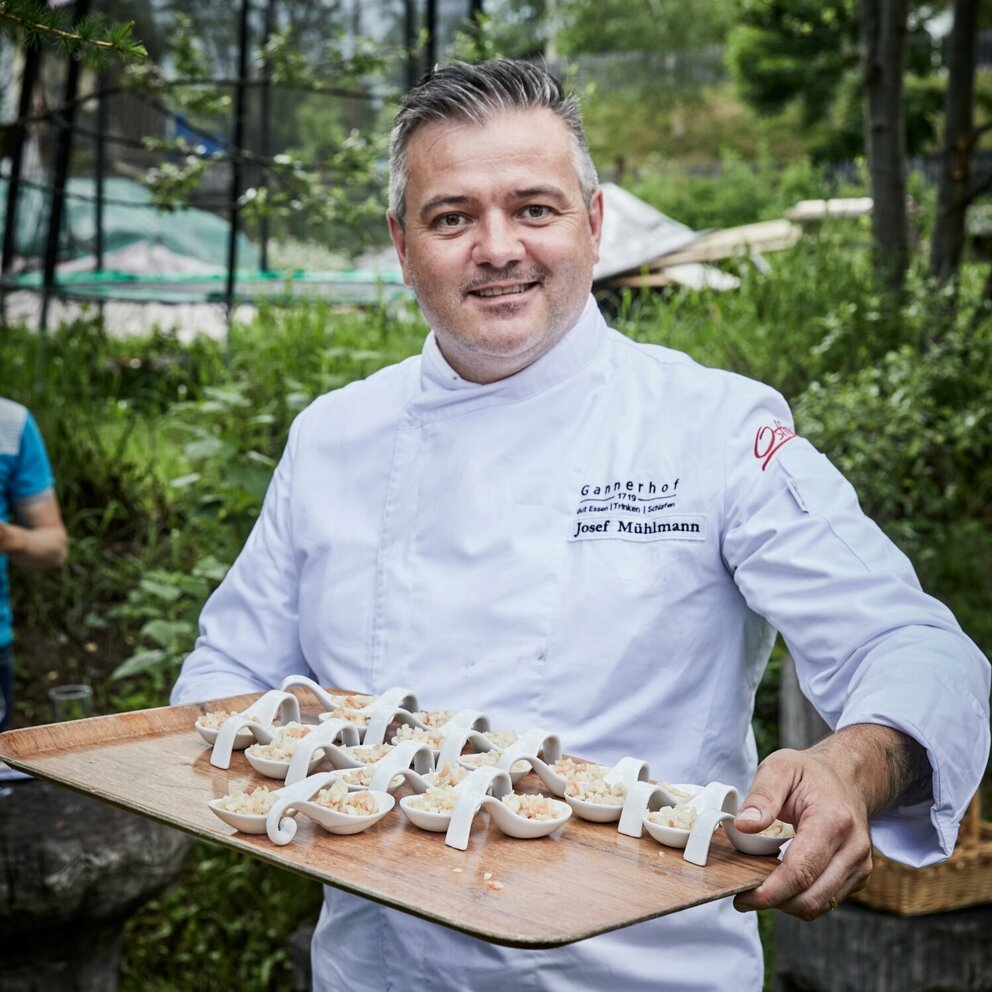 Sternekoch Josef Mühlmann vom Gannerhof in Innvervillgraten Josef Mühlmann vom Gannerhof präsentiert auf einem Tableau in seinen Hände die von ihm zubereiteten und angerichteten Gerichte auf weißen Löffeln.