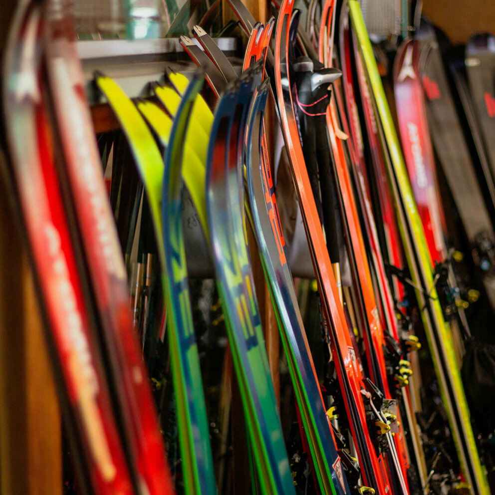 Skiverleih Verschiedene Ski stehen nebeneinander angelehnt an einen Ständer.