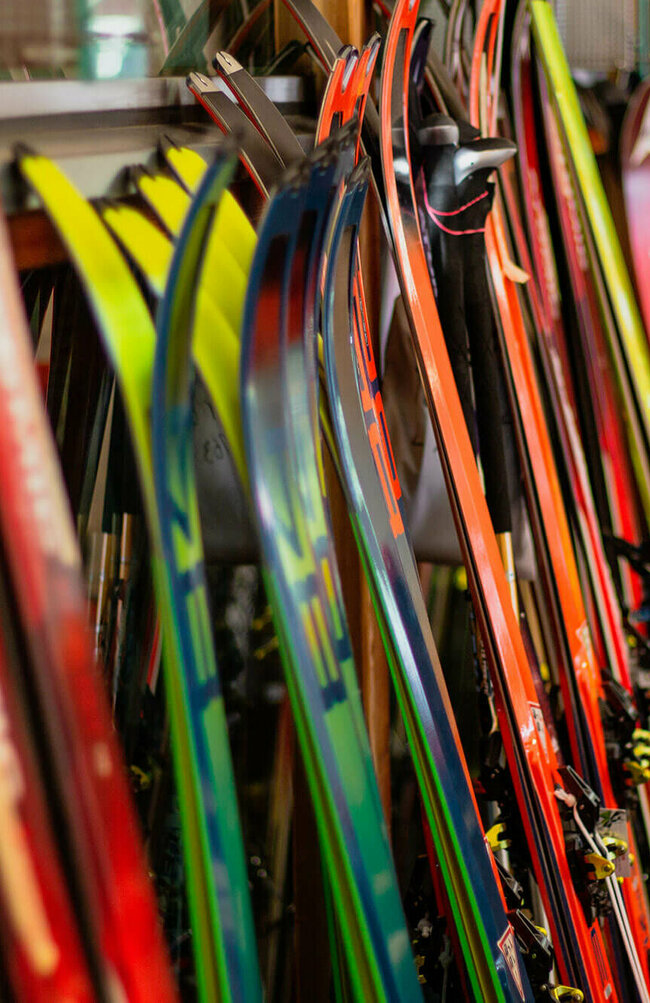 Skiverleih Verschiedene Ski stehen nebeneinander angelehnt an einen Ständer.
