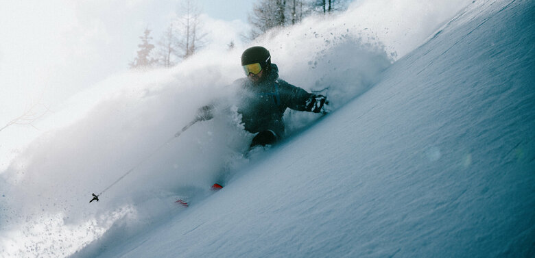 Skitourenfans erwarten Abfahrten vom Allerfeinsten. Ein Skitourenfahrer bei der Abfahrt von der Roten Wand im Defereggental. Er fährt durch Tiefschnee und Trägt Helm, Skibrille und Stöcke.