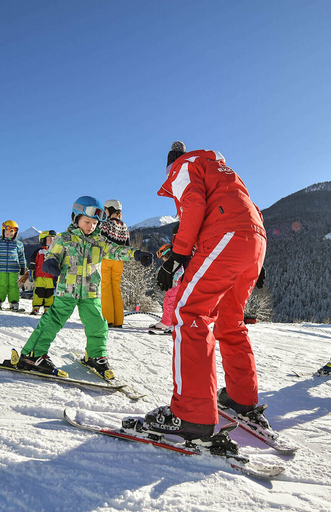 Fellach Lift Virgen Ein rot gekleideter Skilehrer mit mehreren Kindern bei Traumwetter am Fellach Lift in Virgen.