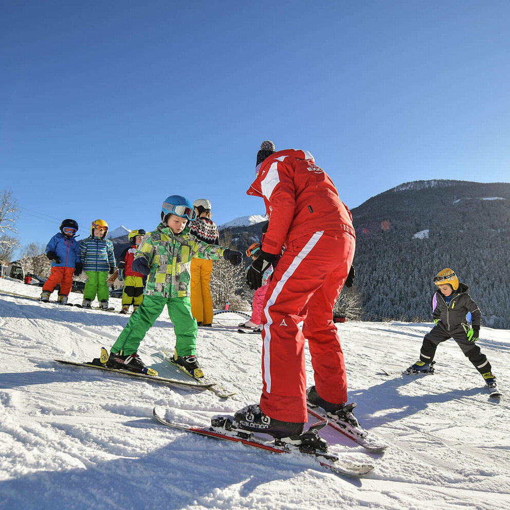 Fellach Lift Virgen Ein rot gekleideter Skilehrer mit mehreren Kindern bei Traumwetter am Fellach Lift in Virgen.