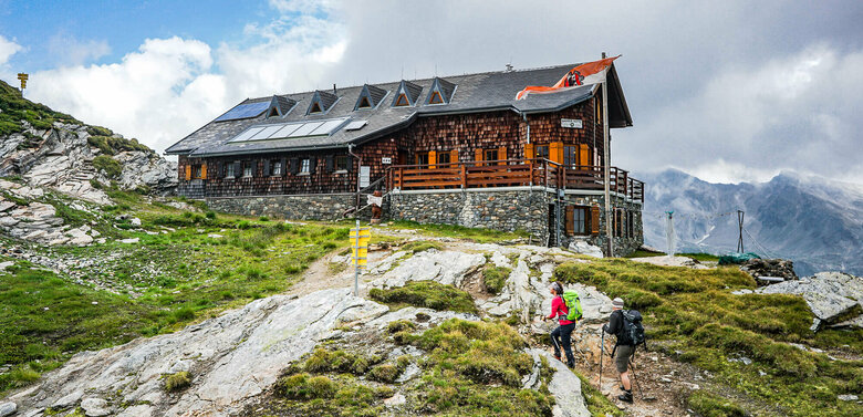Badener Huette am Adlerweg Osttirol Etappe 4 Zwei Personen mit Wanderstöcken auf den letzten Metern vor der Badener Huette am Adlerweg in Osttirol.