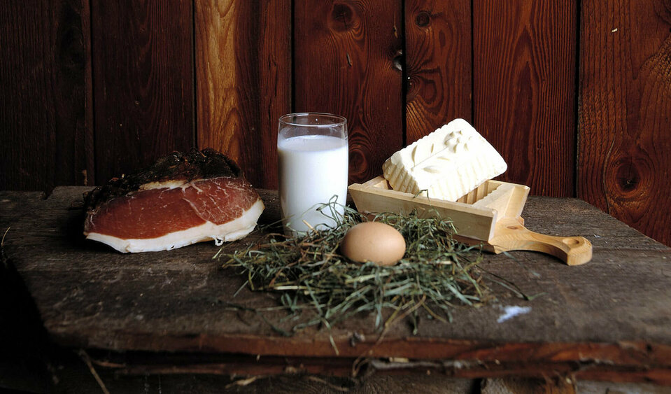 Speck Speck, Butter, Milch und Ei aus eigener Hofproduktion auf einem Brett anschaulich positioniert.