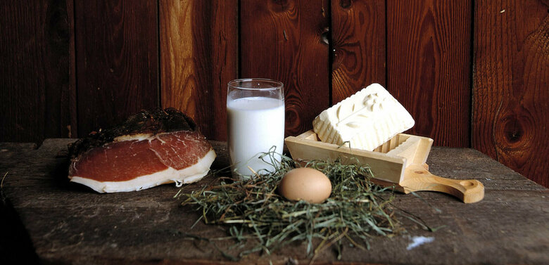 Speck Speck, Butter, Milch und Ei aus eigener Hofproduktion auf einem Brett anschaulich positioniert.
