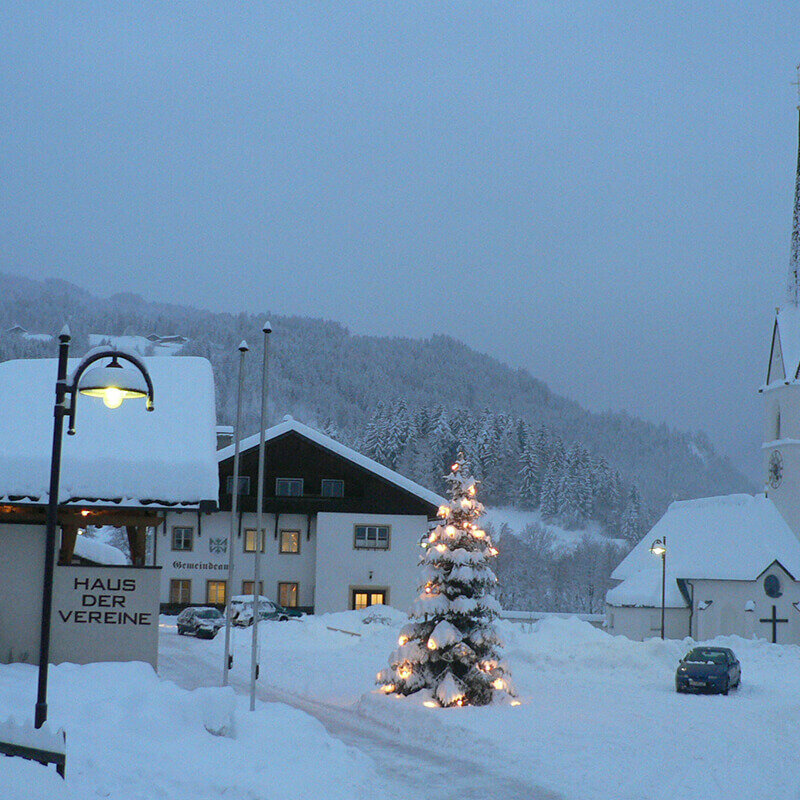 Schlaiten Das tief eingeschneite Dorf Schlaiten mit beleuchtetem Tannenbaum vor der Kirche.
