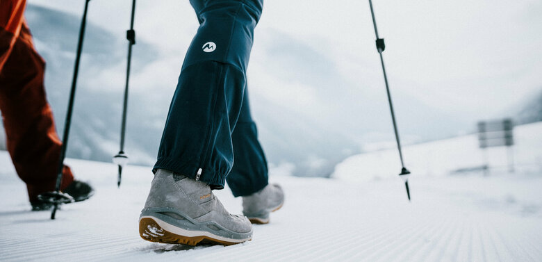 Zwei Personen sind beim Winterwandern auf perfekt präparierten Winterwanderwegen unterwegs.