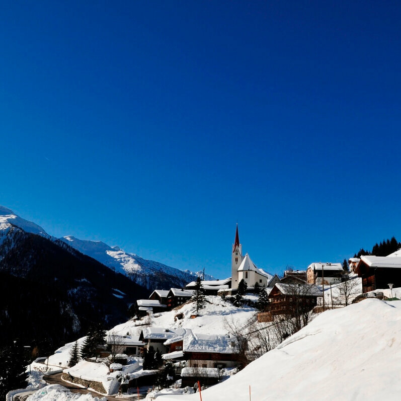 St. Veit Defereggental Blick auf das winterliche St. Veit im Defereggental mit verschneiten Dächern bei Kaiserwetter.